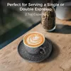 A close-up of an espresso cup with latte art on a saucer, placed on a wooden table. Produktbild-Vorschau