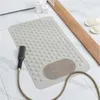 A beige anti-slip bath mat with suction cups is placed on a tiled bathroom floor next to a bathtub. A shower head with a hose is also visible. Produktbild-Vorschau