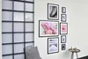 A wall with a grid window and a gallery wall of framed pictures, a chair with a cushion, and a small side table with decorative items. Produktbild-Vorschau