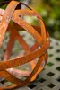 A close-up of a rusty metal sphere on a textured surface. Produktbild-Vorschau
