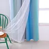 A close-up view of gradient blue and green curtains with white sheer overlay, partially covering a window. A green chair with a small hourglass and cup is in the foreground. Voir les images du produit