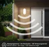 An outdoor LED wall light with a motion sensor is shown mounted on a wooden wall next to a door. The sensor's detection range is illustrated with curved lines. Produktbild-Vorschau