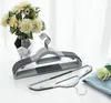 A set of gray plastic hangers is displayed on a white surface, with a vase of flowers in the background. Náhled obrázku produktu