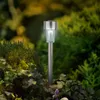 A solar-powered garden light is illuminated among plants and ivy in a garden setting. Produktbild-Vorschau