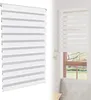 A close-up view of a white zebra roller blind with gray stripes, shown in a studio setting. Voir les images du produit