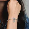 A woman's wrist wearing a silver Pandora bracelet with a dreamcatcher charm. Produktbild-Vorschau