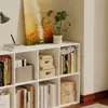 A white bookshelf filled with books, decorative boxes, and a plant, next to a painting of a sunset. Podgląd zdjęcia produktu