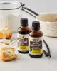 Two bottles of vanilla extract are displayed on a countertop with baking ingredients. Náhľad obrázku produktu