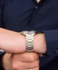 A close-up shot of a person's wrist wearing a silver watch. Produktbild-Vorschau