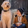 A young boy sits with a dog, holding a mug. Voir les images du produit