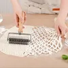 Hands using a pastry wheel to cut lattice strips into dough on a wooden surface. Produktbild-Vorschau