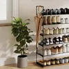 A multi-tiered shoe rack with various shoes and an umbrella, next to a potted plant. Produktbild-Vorschau