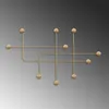 A gold metal wall decoration with a geometric design of lines and spheres. Voir les images du produit