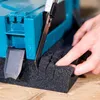 A person is cutting a piece of black foam with a utility knife next to a blue plastic case. Produktbild-Vorschau