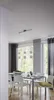 A dining room with a glass-topped table and chairs, illuminated by a modern pendant light fixture. Produktbild-Vorschau