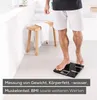 A person is standing on a digital scale in a bathroom. Produktbild-Vorschau