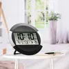 A digital clock sits on a small white table in front of a window with curtains. Anteprima dell’immagine prodotto