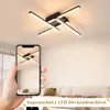 A hand holding a smartphone displaying a ceiling light, with the actual ceiling light visible above. Produktbild-Vorschau