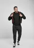 A man is posing in a studio setting, wearing a black jacket and pants. Anteprima dell’immagine prodotto