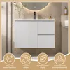 A white bathroom vanity with two drawers and a door, mounted on the wall, with a round mirror and faucet above it. The background features a wood-paneled wall and beige tiles. Four circular icons with text are displayed at the bottom. Náhled obrázku produktu