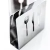 A close-up shot of a stainless steel napkin holder with cutouts of a fork and knife. Produktbild-Vorschau