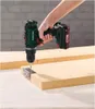 A person is using a cordless drill to attach a metal hinge to a wooden plank. Produktbild-Vorschau