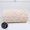 A beige blanket with a cable knit pattern is shown against a white background. Anteprima dell’immagine prodotto