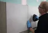 A person is tiling a wall with large tiles. Produktbild-Vorschau