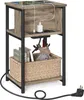 A three-tiered side table with a wood-grain finish and black metal frame, featuring integrated charging ports and a woven basket. Produktbild-Vorschau