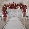 A wedding arch decorated with red and white flowers, set up on a white aisle with chairs on either side. Náhled obrázku produktu