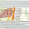 Orange-weißer Abstauber, von einer Hand gehalten, reinigt weiße horizontale Fensterjalousien Anteprima dell’immagine prodotto