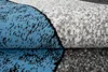 A close-up, folded view of a rug with a geometric pattern in blue, gray, black, and white. Náhľad obrázku produktu