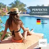 A woman in a bikini and hat sits on a lounge chair by a pool, enjoying a vacation. Produktbild-Vorschau