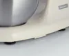 Close-up of the base of a vintage-style kitchen mixer, showing its cream-colored body and silver bowl. Náhled obrázku produktu