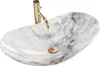 A close-up studio shot of a marble-patterned vessel sink with a gold faucet. Náhled obrázku produktu