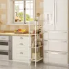 A kitchen scene featuring a refrigerator, oven, and a white shelving unit with various kitchen items. Produktbild-Vorschau