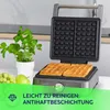 A waffle maker with two waffles inside, next to a potted plant and some fruit. Náhľad obrázku produktu