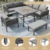 An outdoor patio furniture set, including a sectional sofa, a table, and a bench, arranged on a rug on a patio. Produktbild-Vorschau