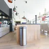 A modern kitchen with a stainless steel trash can in the foreground, next to a wooden island. Anteprima dell’immagine prodotto