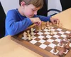 A young boy playing chess on a wooden chessboard. Podgląd zdjęcia produktu