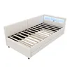 A white upholstered daybed with a slatted mattress base and a headboard with integrated LED lighting and storage compartments. Podgląd zdjęcia produktu