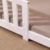 Close-up view of the side of a white wooden bed frame with a light brown mattress. Náhľad obrázku produktu