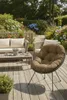 A cozy outdoor seating area with a sofa, chairs, and a coffee table on a wooden deck, surrounded by lush greenery and flowers. Produktbild-Vorschau