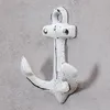 A white anchor-shaped wall hook mounted on a gray, textured wall. Produktbild-Vorschau