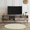 A modern TV stand with a television on top, placed in a well-lit room with white paneled walls and a wooden floor. Produktbild-Vorschau