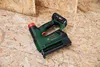 A cordless tacker is placed on a wooden surface. Produktbild-Vorschau