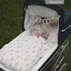 A baby in a stroller with a blanket and toys. Produktbild-Vorschau