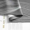 A close-up view of a gray curtain with a white wavy line pattern, showing text on a white surface underneath. Produktbild-Vorschau