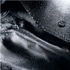A close-up, abstract view of a black fabric surface covered in water droplets, with a small metallic object visible. Anteprima dell’immagine prodotto