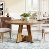 A round wooden dining table is set in a dining room with chairs and a rug. Anteprima dell’immagine prodotto